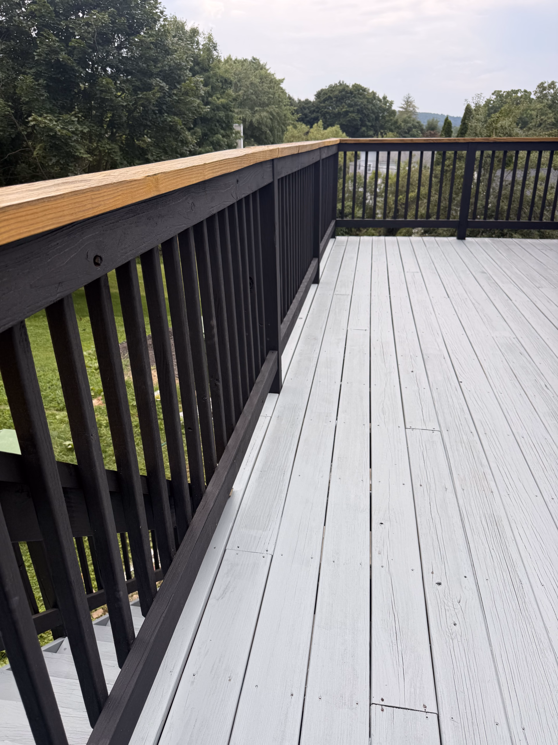 Black solid stain railing and warm-toned handrail on refinished deck in Bethel CT