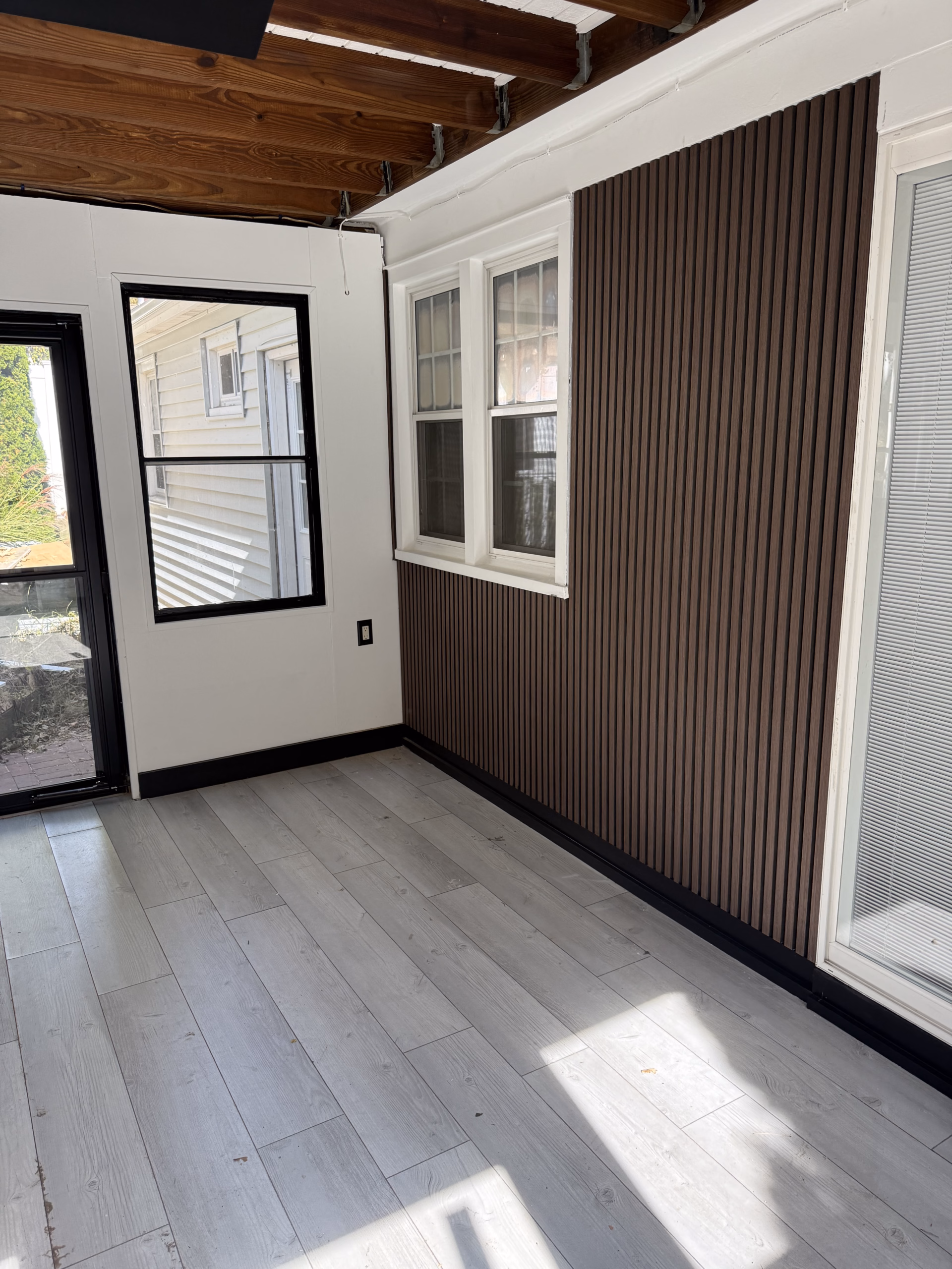 Enclosed porch renovation dark accent panel and white walls in New Haven CT